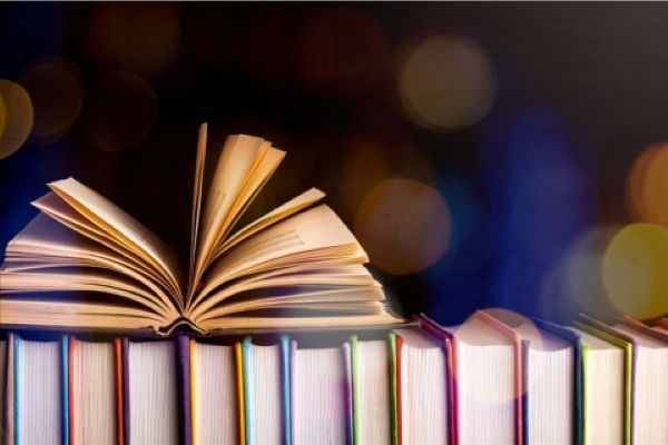 row of books with one book opened on top.