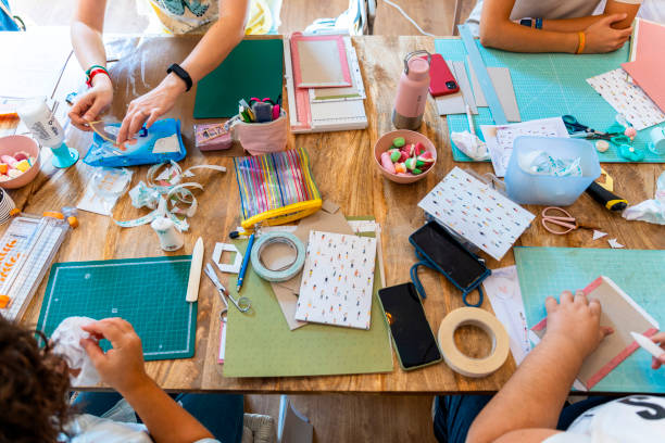 Four people gathered around a table full of crafting supplies.