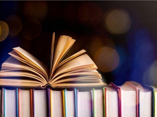 row of books with one book opened on top.