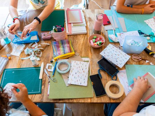 Four people gathered around a table full of crafting supplies.